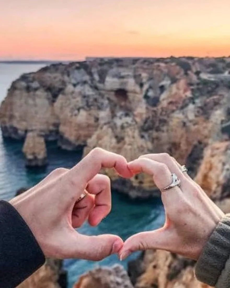 A couple’s hands forming a heart in soft evening light