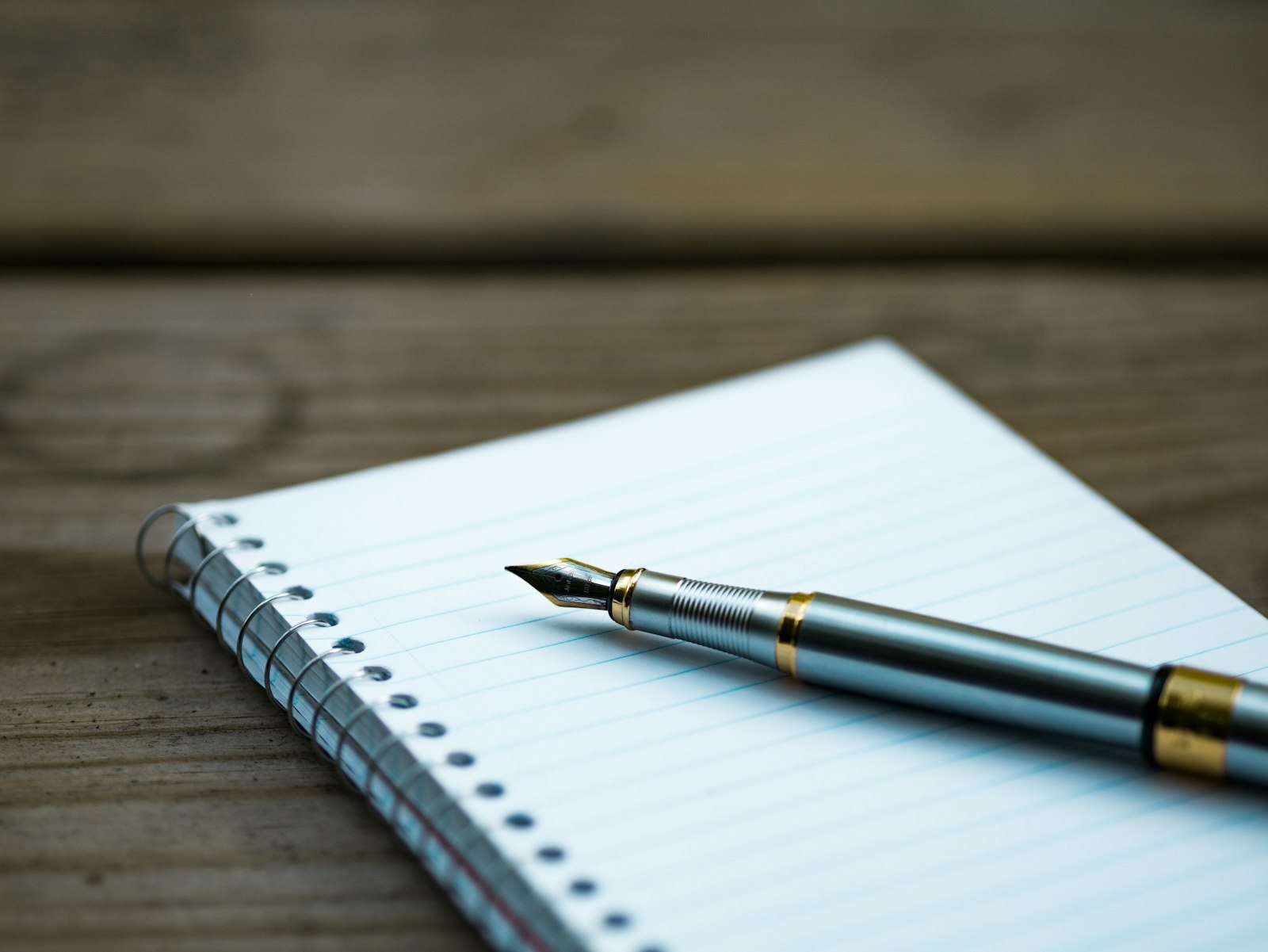 A fountain pen resting on a lined notebook