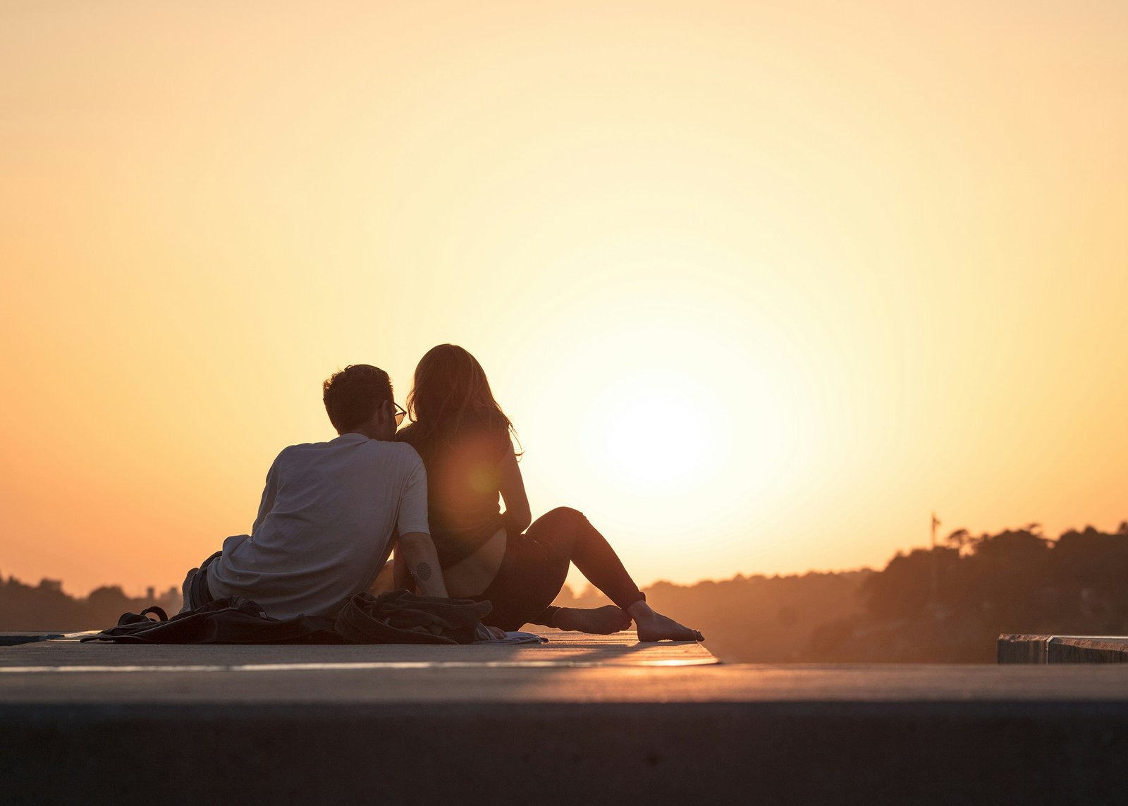 A couple sitting close together, watching the sunset
